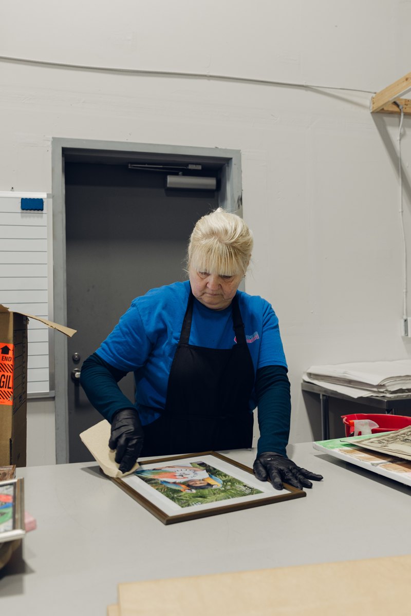 A technician hand-cleaning a framed family photograph