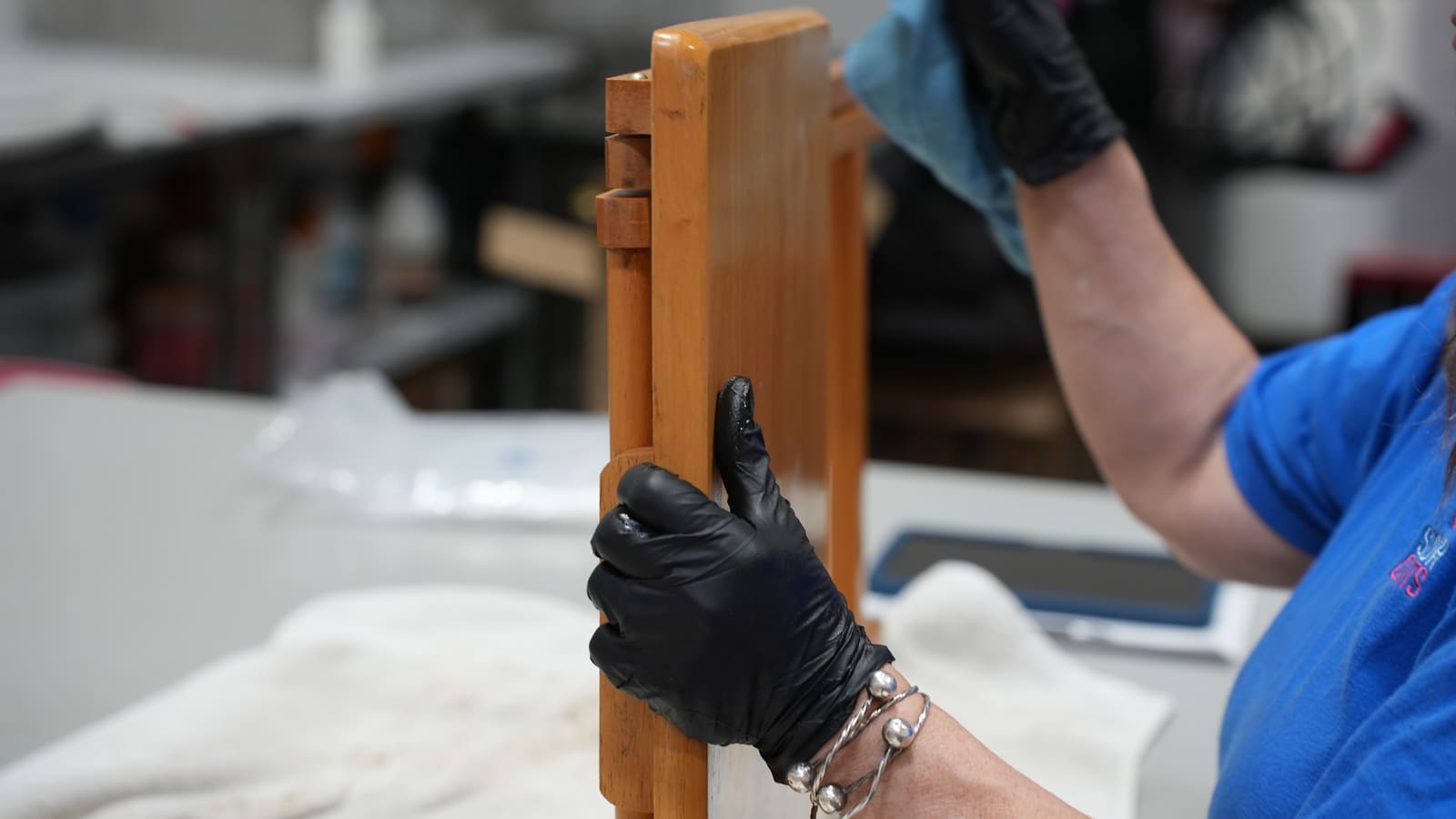 A team member cleaning a wooden chair by hand at our facility