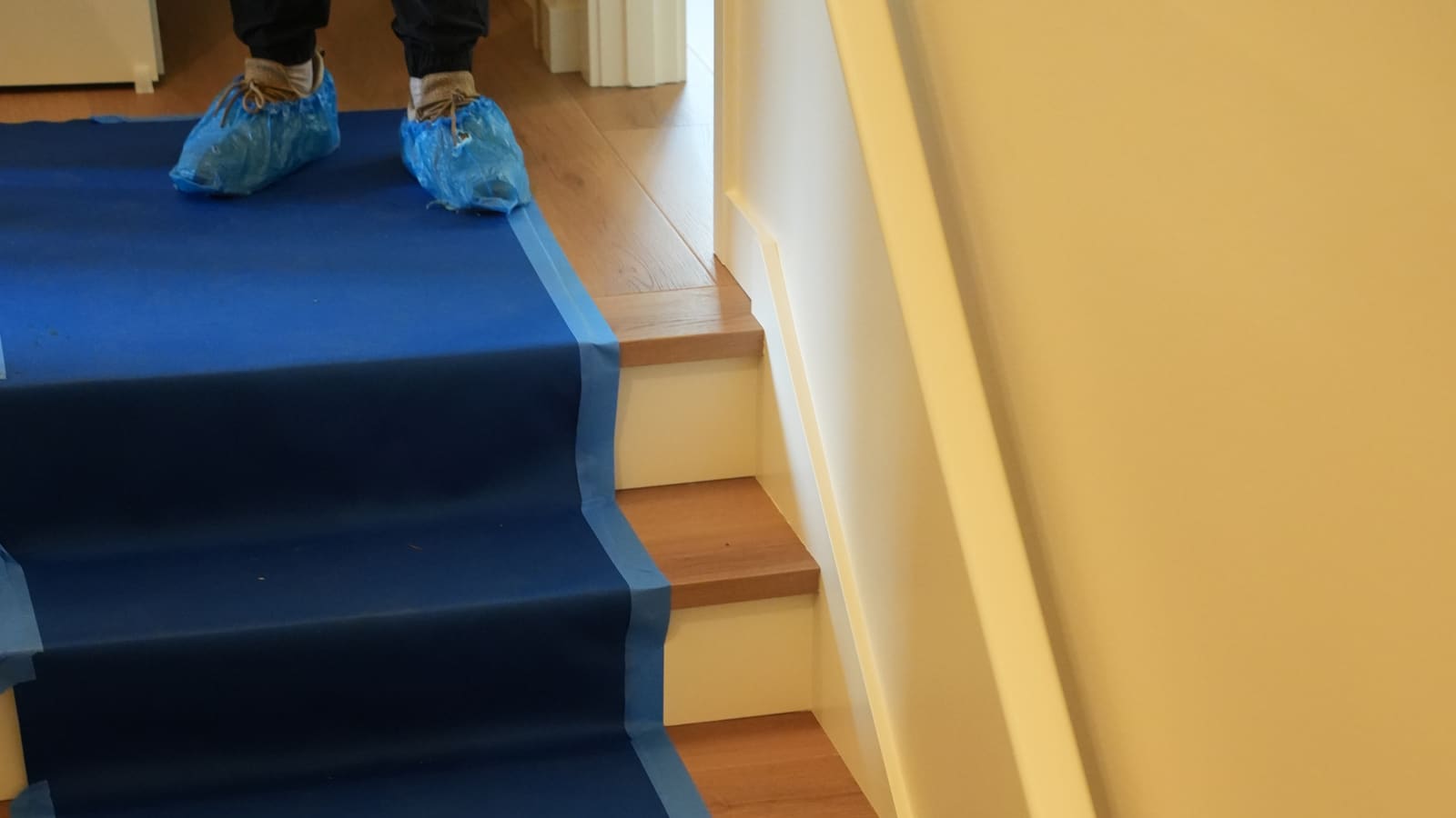 Protective covering taped down the stairs while the crew works in shoe covers